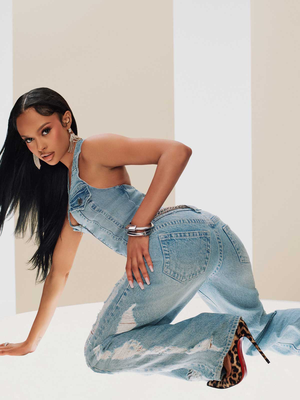 Woman wearing a true religion denim tank top, true religion bootcut light wash low rise jeans, and cheetah print heels