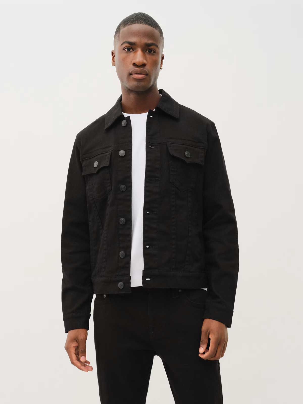 man wearing true religion denim trucker jacket with black jeans