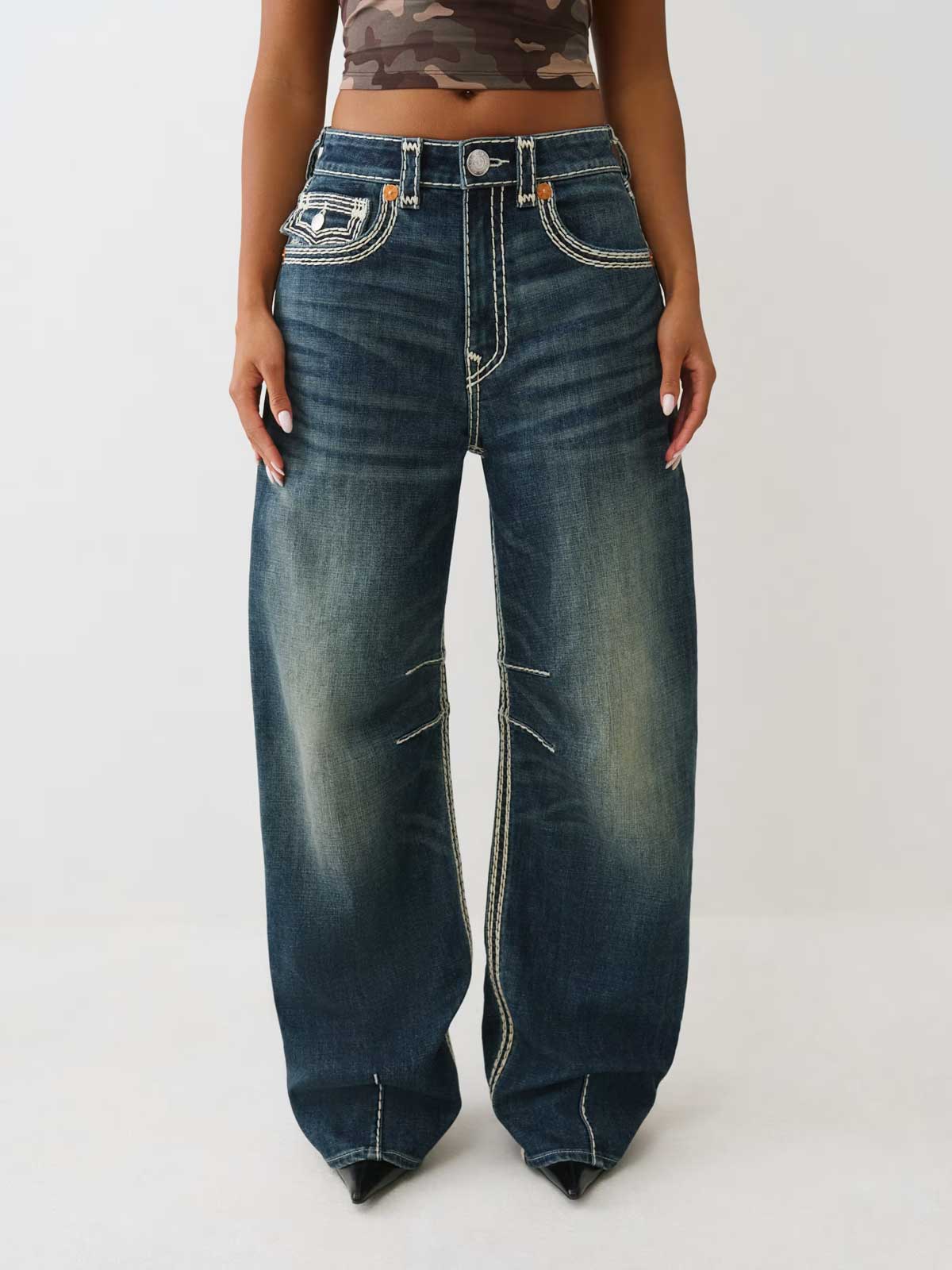 woman wearing true religion dark wash bailey super qt barrel jeans with camo baby tee